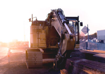 Digger parked on the side of the road in front of some aluminium beams at sunrise